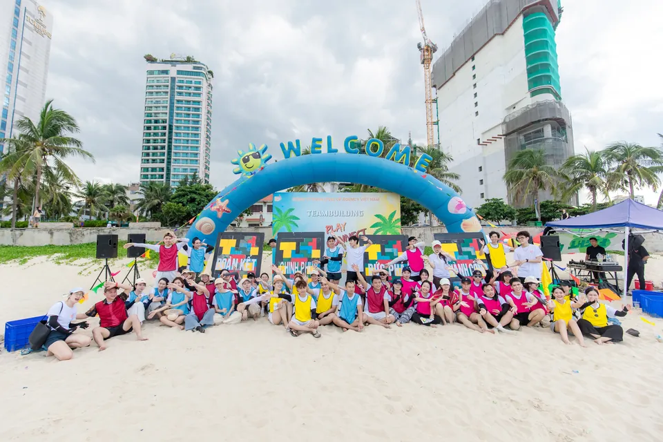 The whole company in team colours on the beach at teambuilding in Da Nang