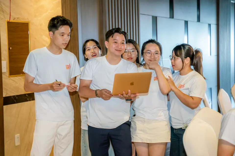 A product team reviewing work together on one laptop